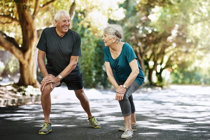 Photo d'un couple de personnes âgées s'échauffant avant d'aller courir dehors